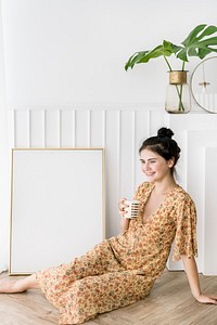 Cute happy girl with a coffee mug sitting by a frame mockup