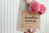 Woman holding a woven tote bag mockup with pink hydrangea