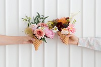 Two women holding up flowers in ice cream cones