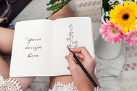 Woman sitting by fresh flowers and writing on her diary