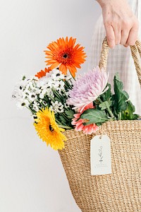 Colorful tropical flowers in a woven bag with a card mockup