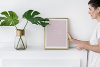 Woman putting a frame mockup by the monstera vase