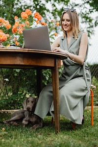 Happy woman working on her laptop in the garden