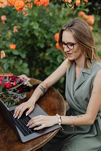 Happy woman working on her laptop in the garden