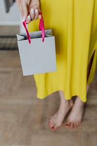 Woman in a  yellow dress holding a gray paper bag