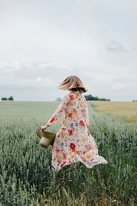 Woman in a floral dress with a woven hat in a field