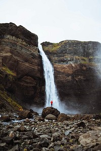 Man in a red jacket at the Haifoss waterfall, Iceland