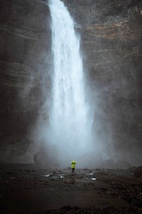 Woman in a green jacket at the Haifoss waterfall, Iceland