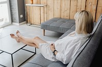 Pregnant blond-haired woman relaxing on a gray sofa