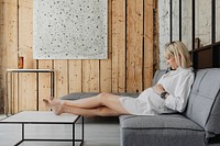 Pregnant blond-haired woman relaxing on a gray sofa