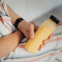 Woman holding cold-pressed detox juice bottle mockup