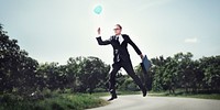 Businessman holding a balloon in nature