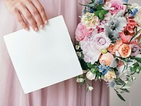 Bride holding a save the date card with a bouquet of flowers