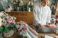 Smiling woman using a laptop in flower shop