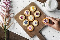 Hand taking a piece of homemade cookies with floral garnish next to a coffee cup