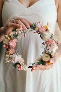 Woman wearing an engagement ring holding a flower wreath made with exotic flowers