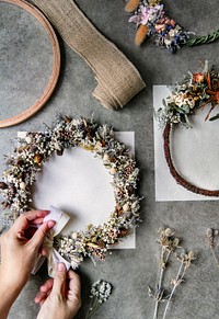 Woman tying a ribbon on a floral wreath  over a white card mockup