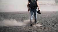 Rear view of a man walking on dusty land