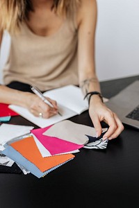 Female fashion designer writing on her notebook