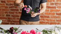 Man cutting flowers in his hands while making a bouquet
