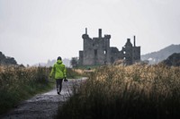 Rear view of a female photographer in front of Kilchurn Castle, Scotland