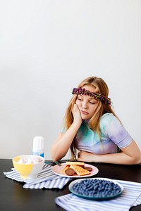 Bored woman sitting by a plate with waffles 