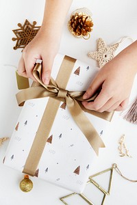 Woman tying a gold ribbon to a white present