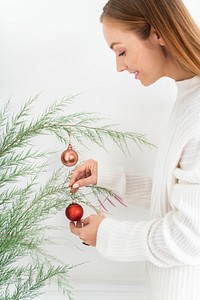 Woman hanging a red bauble on a Christmas tree