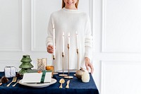 Woman decorating a Christmas dining table with candles