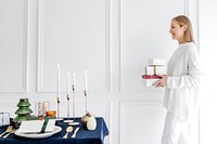 Blond woman carrying presents close to a dining table