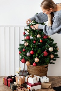 Blond girl decorating a Christmas tree with ornaments