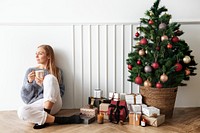 Blond girl sitting next to a Christmas tree