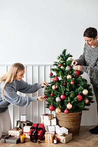 Woman decorating a Christmas tree with ornaments
