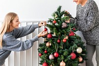 Woman decorating a Christmas tree with ornaments