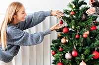 Woman decorating a Christmas tree with ornaments