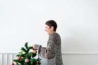Cheerful woman decorating a Christmas tree with ornaments