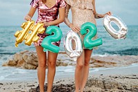 Girls carrying a 2020 foil balloon at the beach party