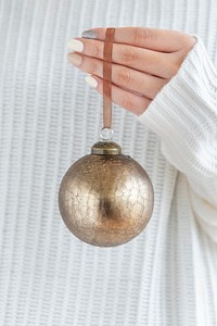 Woman in a white sweater holding a gold bauble
