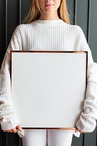 Woman in a white sweater holding a wooden frame mockup
