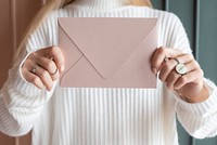 Woman in a white sweater holding a pink envelope