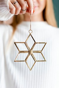 Woman showing a gold snowflake Christmas ornament