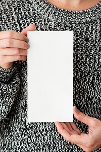Woman in a gray sweater holding an earth tone card mockup