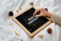 Woman making a Merry Christmas word on a black text board