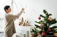 Cheerful woman decorating a Christmas tree with ornaments