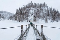 Woman crossing a suspension bridge in a snowy Oulanka National Park, Finland