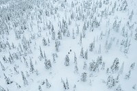 Drone shot of people trekking in a snowy forest in Lapland, Finland