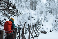 Woman crossing a suspension bridge in a snowy forest, Finland