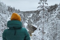 Hiker standing by a river in the snowy forest