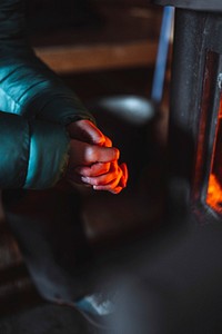 Woman warming up near a fireplace in a hut