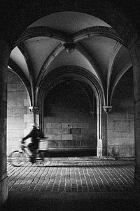 Man riding a bicycle down cobblestone streets